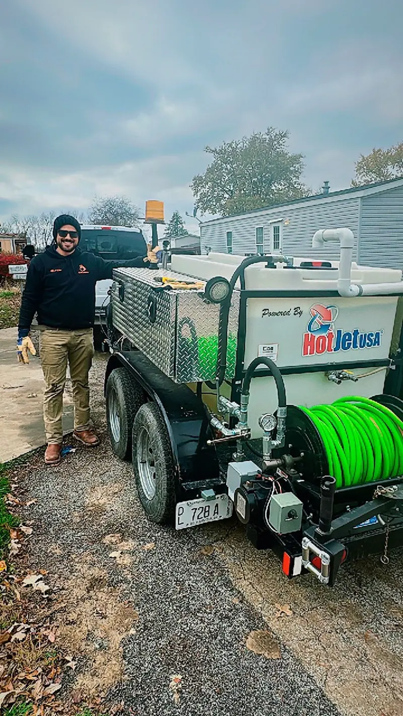 OX technician next to the HotJet hydro jetting trailer used to clear sewer and drain lines.
