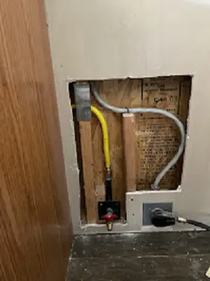 Wall opening with a gas flex line and outlet prepared for a water heater installation.
