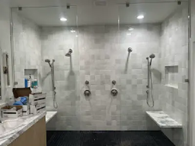 Large walk-in shower with multiple shower heads installed.