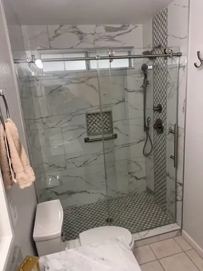 Shower remodel with marble-look walls and a glass door.