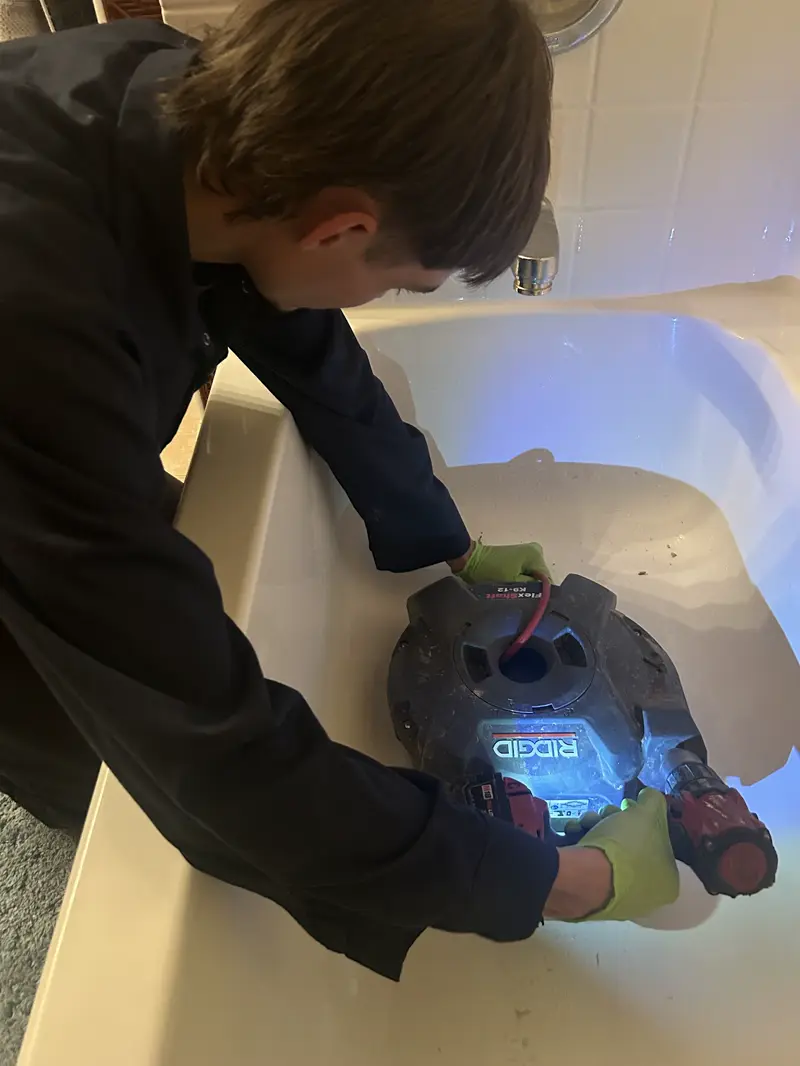 Technician working on a tub drain with a work light.