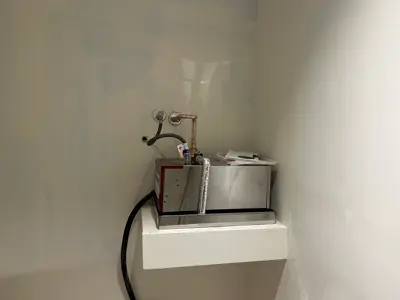 Small point-of-use water heater installed on a shelf.