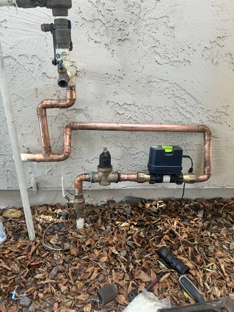 Exterior copper water line with a smart water shutoff valve and pressure regulator for leak protection.