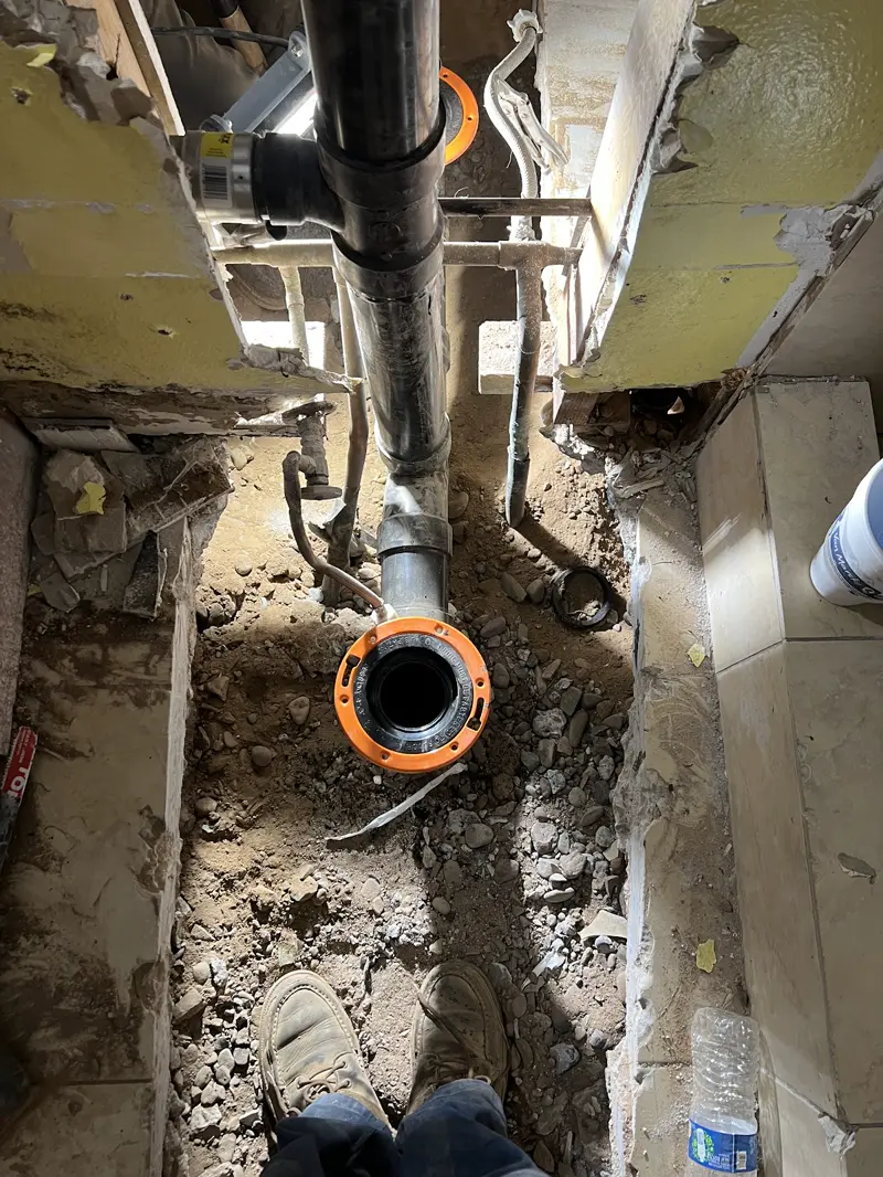 Trench cut through a concrete slab with the sewer line exposed for repair.