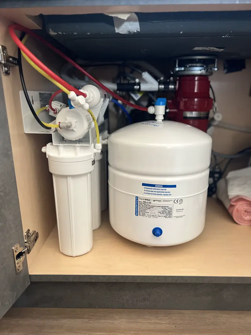 Under-sink reverse osmosis drinking water system installed next to a garbage disposal.