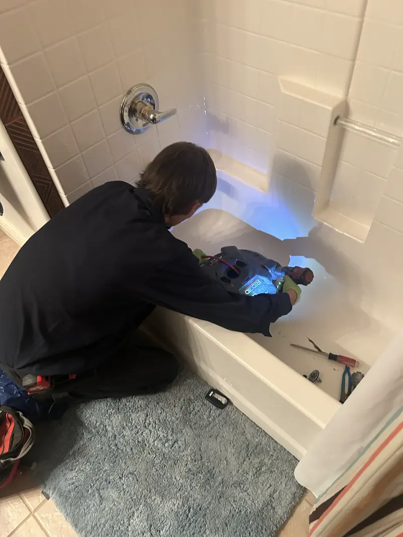 Technician repairing a tub and shower valve.