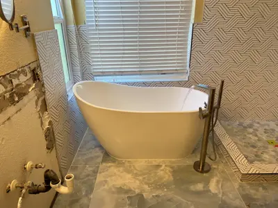 Freestanding tub and floor-mount tub filler being installed during a bathroom remodel.