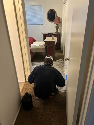 Technician laying floor protection in a hallway before plumbing work.
