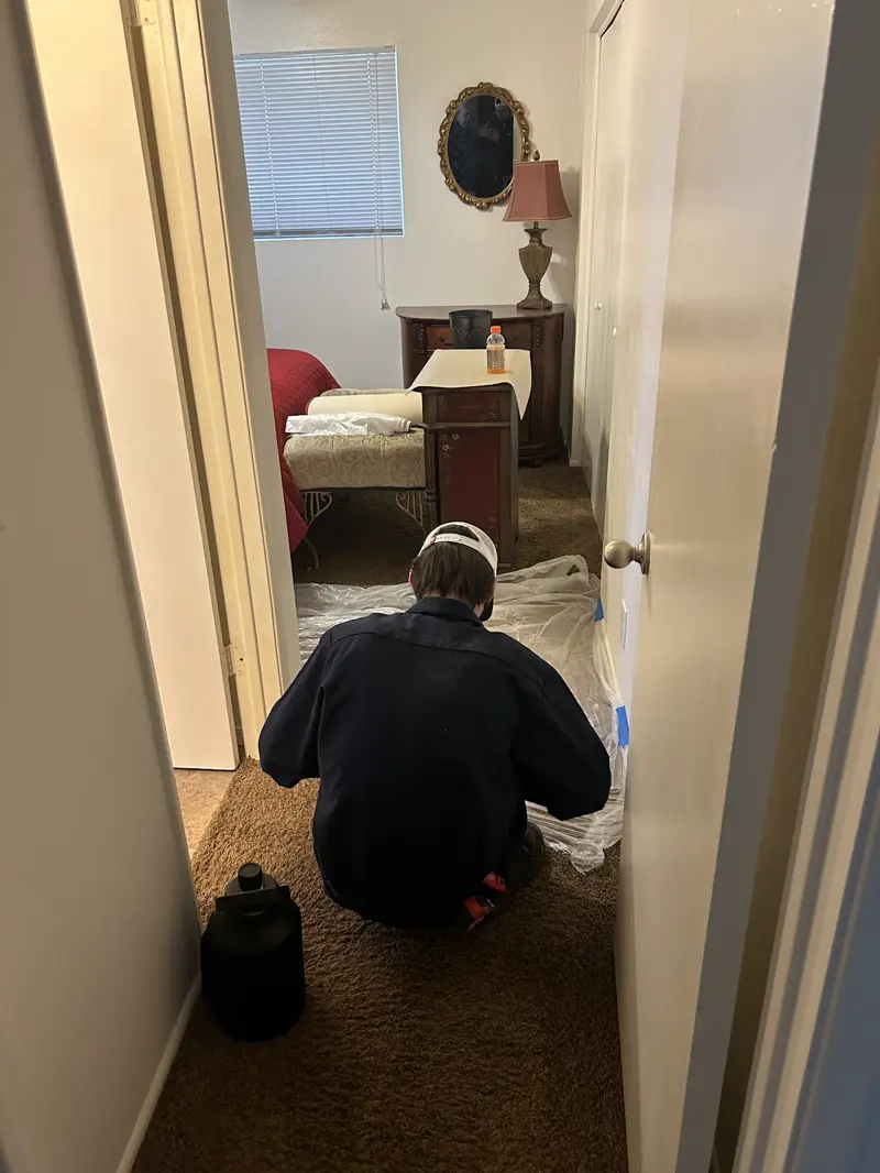 Technician laying floor protection in a hallway before plumbing work.
