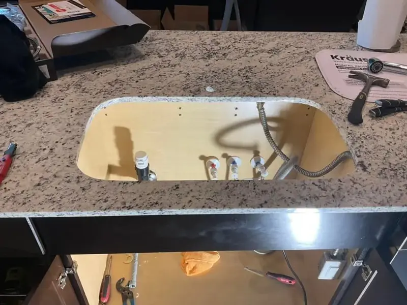 Countertop sink cutout with new water supply lines ready for the faucet.