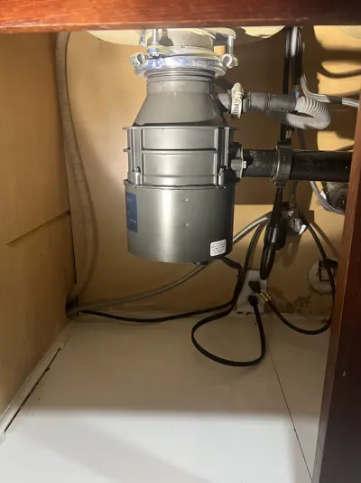 New garbage disposal installed under a kitchen sink.